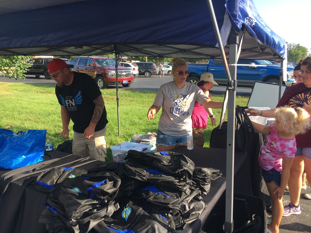 Julie Schmidt hands out backpacks at the CNE CARES tent during the open house and school supply fair Aug. 12. (Photo by Dick Maloney.)