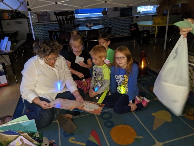 Clermont Northeastern Elementary School students and parents read under a tent set up in the school library during fall curriculum night.